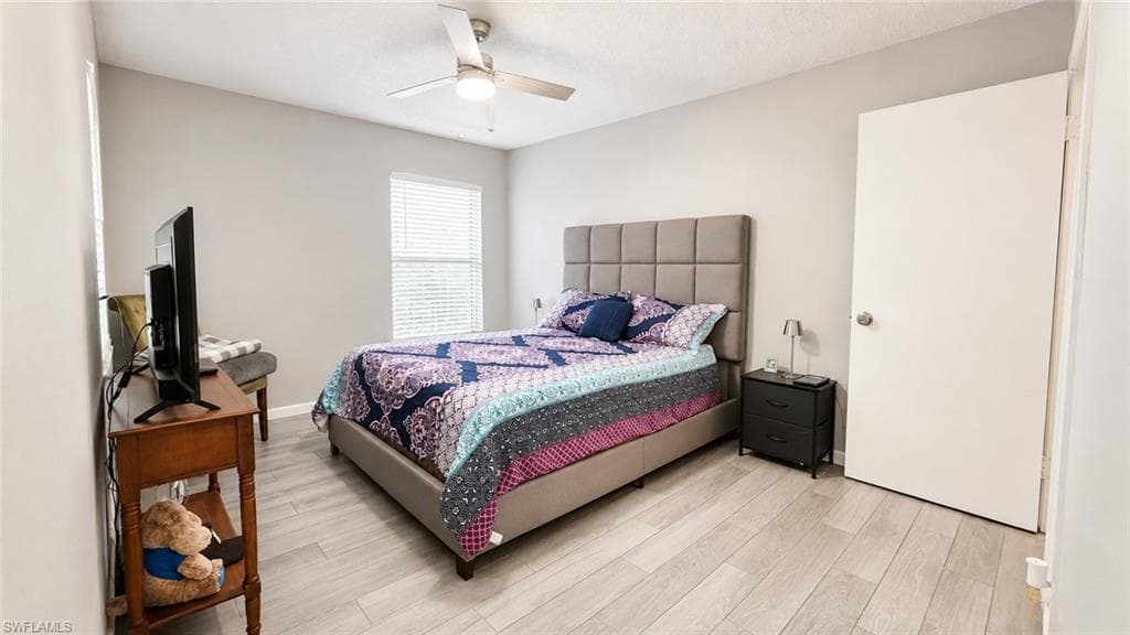 Ceiling fan with integrated lighting, wood-finish flooring, and a window with blinds