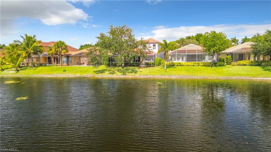 Waterfront property with expansive green lawn, mature landscaping, and screened outdoor living areas