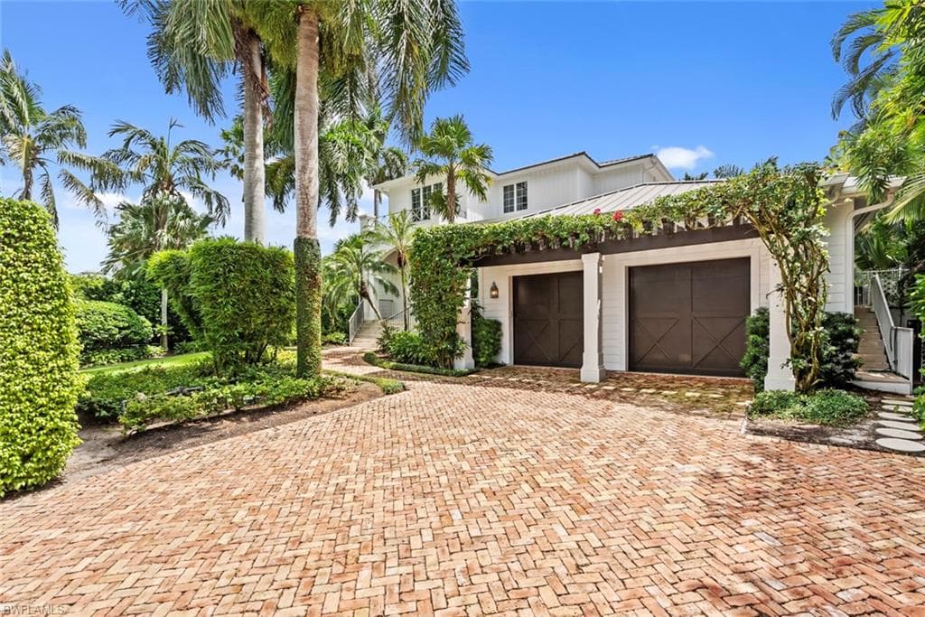 Brick paver driveway leading to a two-car garage with wood-finish doors