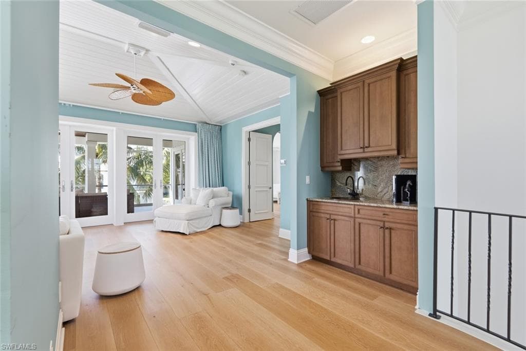 Wood-finish flooring throughout, featuring a wet bar with dark wood cabinetry and stone backsplash