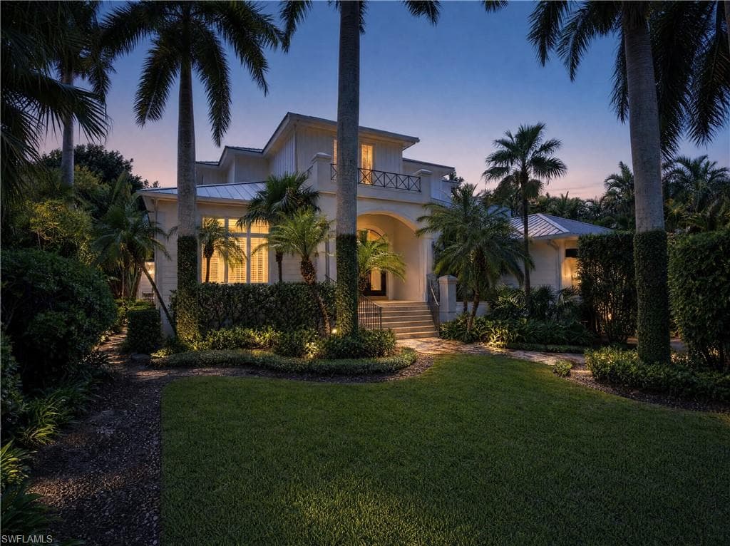 Stucco exterior with a tiled roof, elevated entry, and a second-story balcony