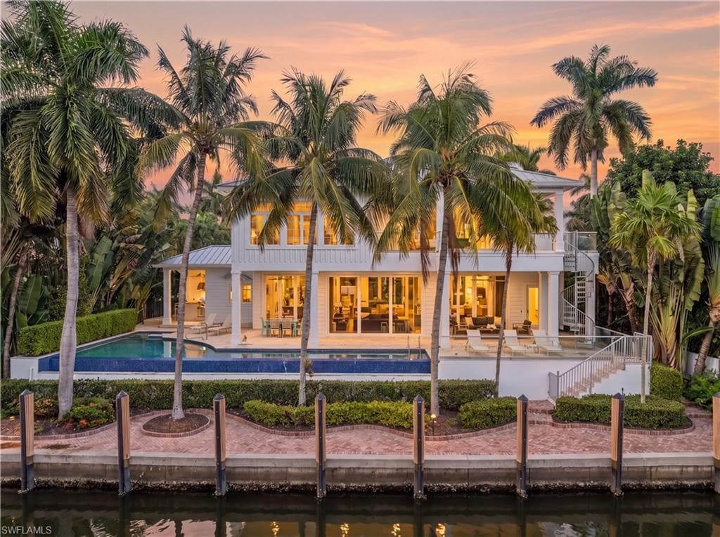 Waterfront property featuring a private boat dock, expansive patio with a swimming pool, and a spiral staircase accessing an upper-level balcony
