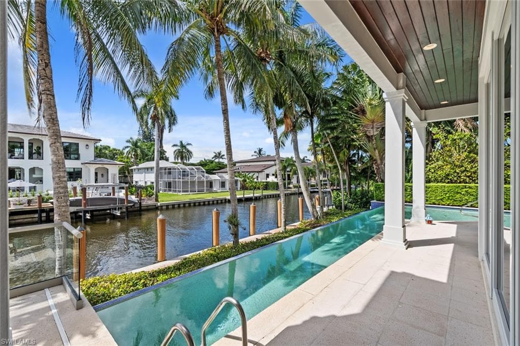 Outdoor patio with an integrated linear pool, glass railing, and wood-finish ceiling