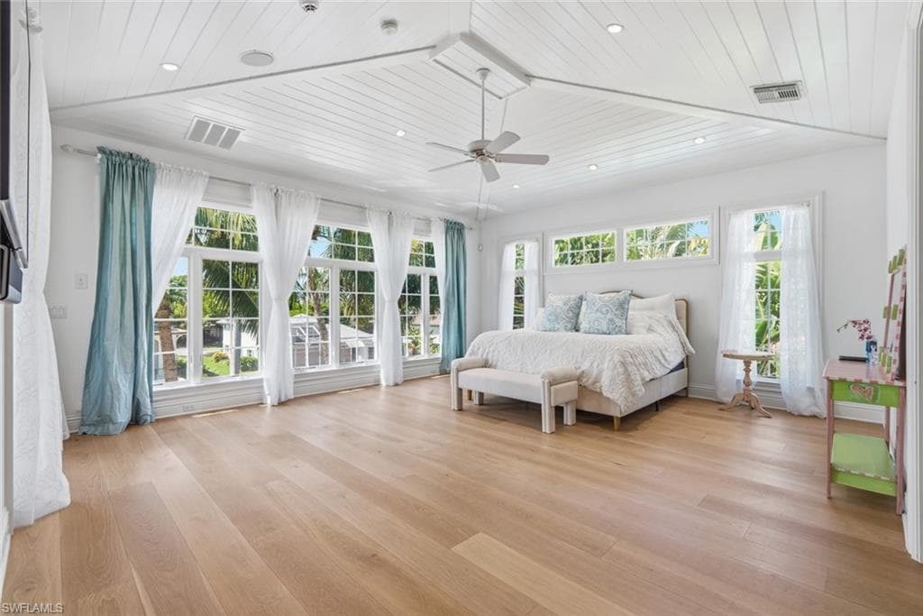 Spacious room featuring wood-finish flooring, multiple windows, a slatted ceiling, and recessed lighting