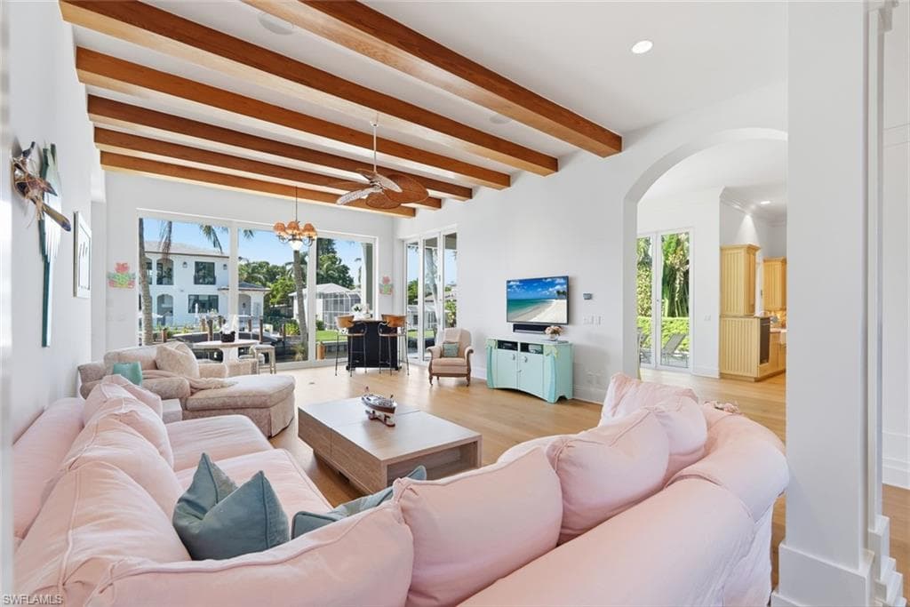 Vaulted ceiling with exposed wood beams, hardwood-finish flooring, recessed lighting, and an arched doorway