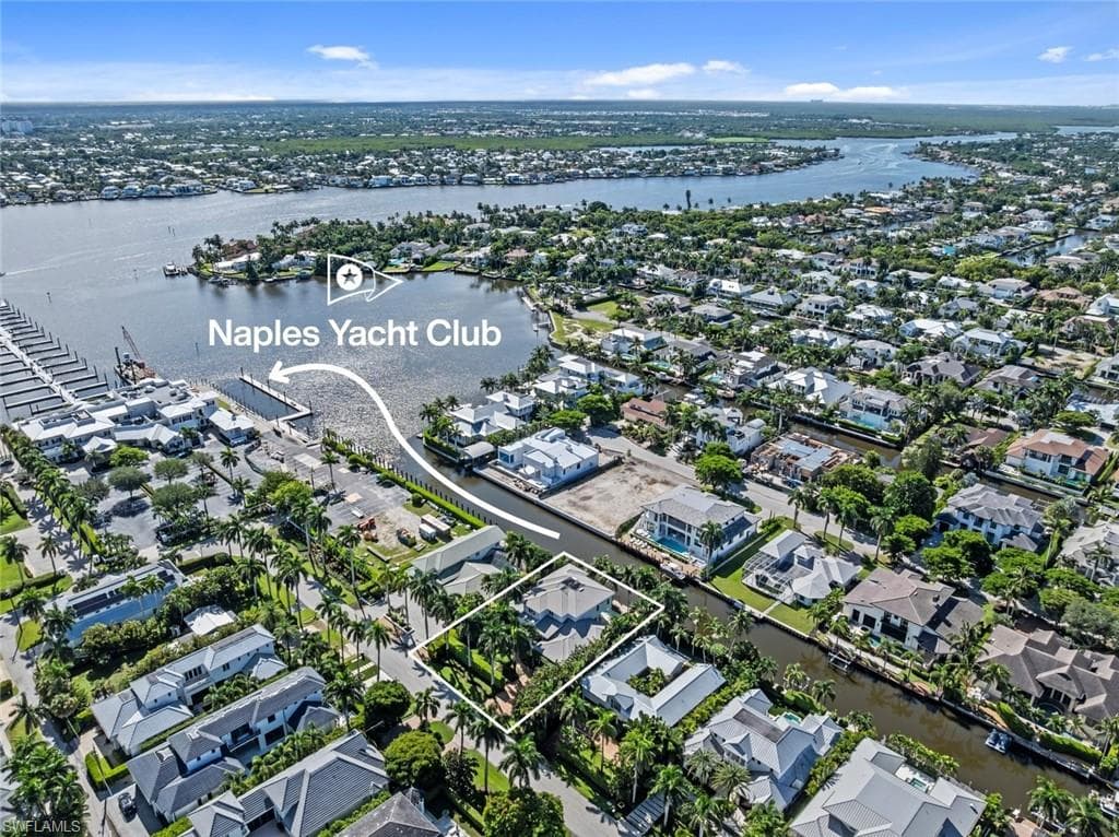Aerial perspective showcasing a waterfront community with numerous residential properties, surrounding waterways, and the Naples Yacht Club