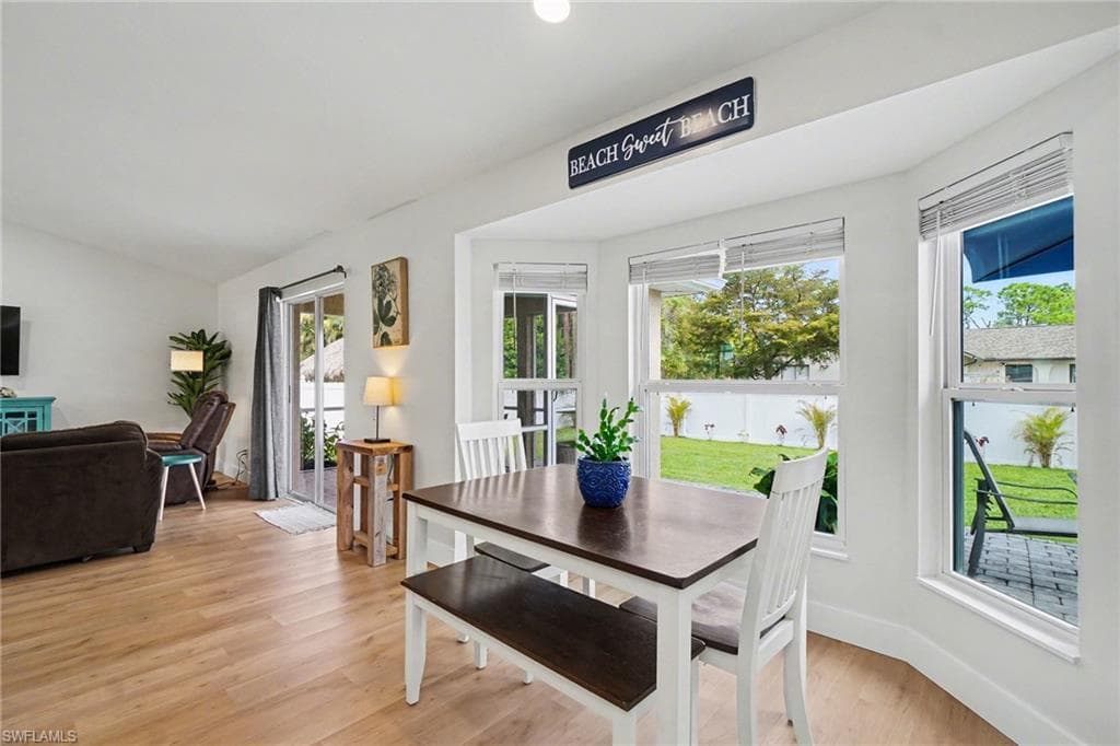 Bay windows, wood-finish flooring, white walls, and a sliding glass door to the exterior