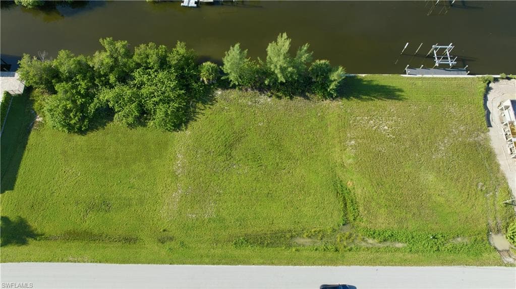 Cleared lot featuring direct water frontage, a concrete seawall, and mature tropical landscaping