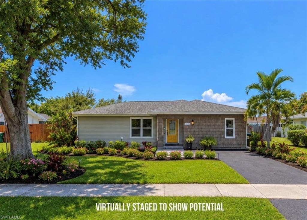 VIRTUALLY STAGED LANDSCAPING Ranch-style residence featuring a gray exterior, a yellow entry door, and a black paved driveway