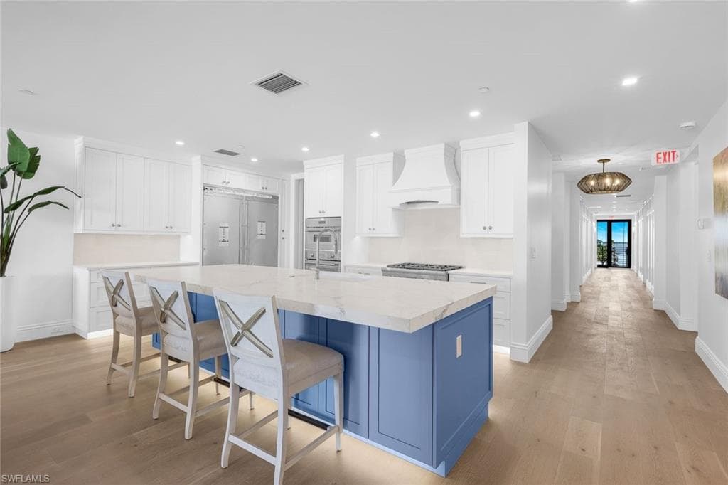 Kitchen with two tone cabinetry, an island with sink, a kitchen breakfast bar, recessed lighting, and built in refrigerator