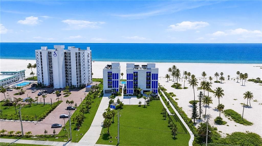 Beachfront property featuring white sand, tropical palms, and a clear blue ocean - Virtually Edited Image