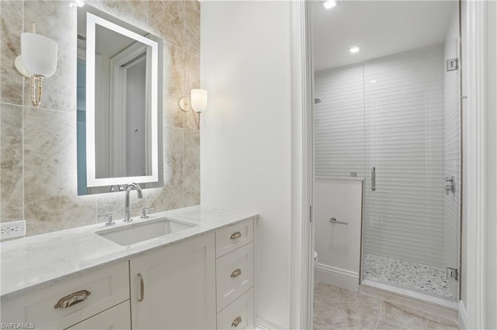 Full bath with vanity, a stall shower, tile walls, and recessed lighting