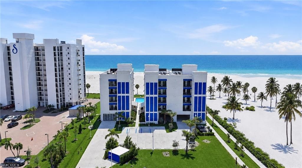 Beachfront property featuring white sand, tropical palms, and a clear blue ocean - Virtually Edited Image