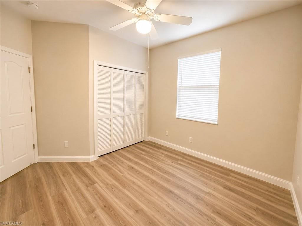 Wood-finish flooring, louvered bi-fold closet doors, ceiling fan with light fixture, window with blinds