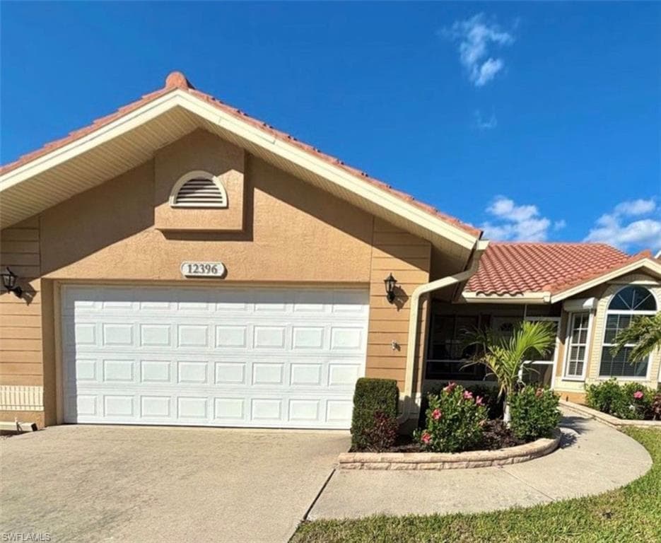 View of front facade with driveway, stucco siding, and a garage