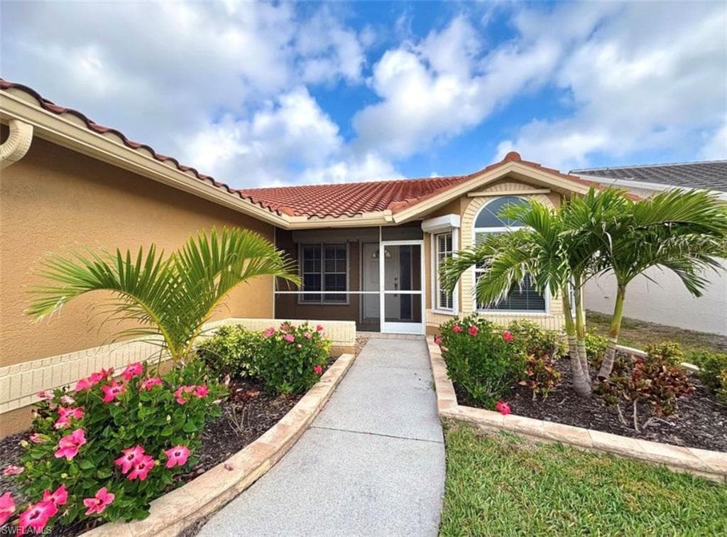 Doorway to property featuring a sunroom, a tiled roof, and stucco siding