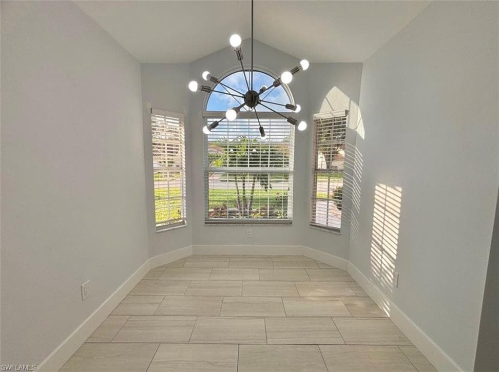 Unfurnished dining area featuring baseboards and lofted ceiling