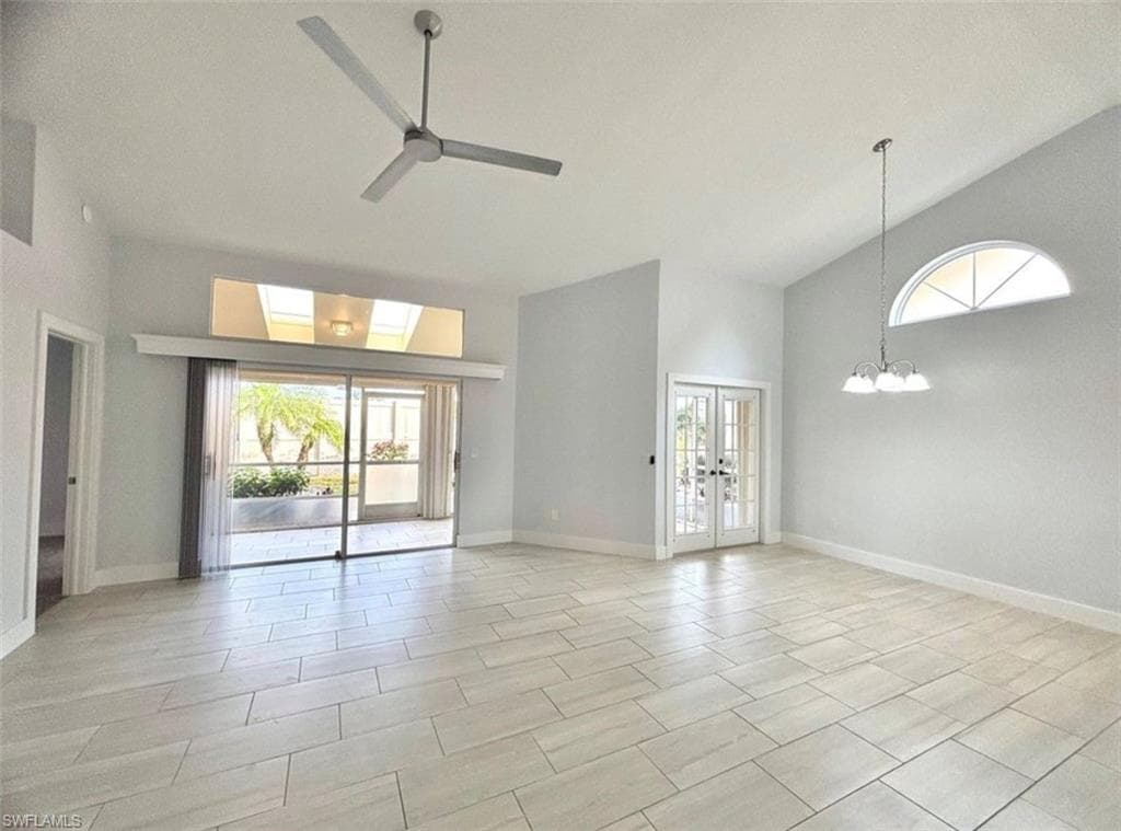 Spare room featuring french doors, vaulted ceiling, a ceiling fan, and hanging lights