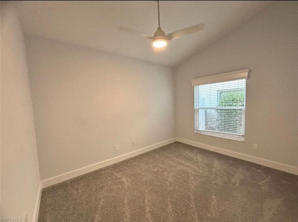 Empty room featuring vaulted ceiling, carpet, and ceiling fan