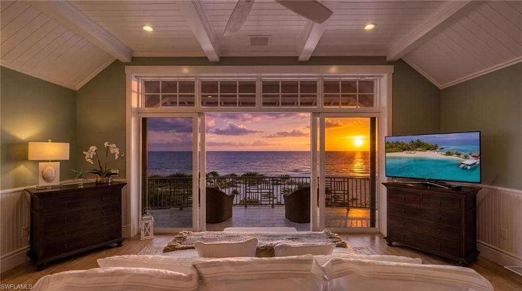 Hardwood-style flooring, vaulted ceiling with exposed beams, sliding glass doors to a private balcony, and recessed lighting