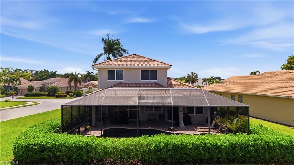 Two-story exterior with a tile roof, screened enclosure, and a swimming pool