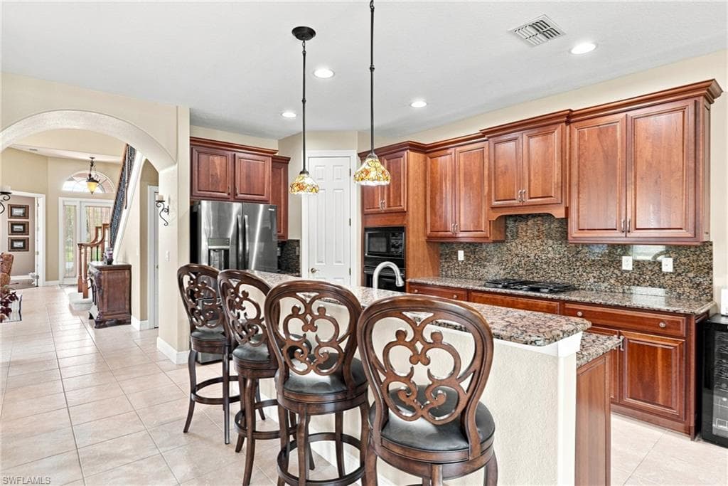 Kitchen featuring extensive wood cabinetry, granite countertops, tile backsplash, and stainless steel appliances