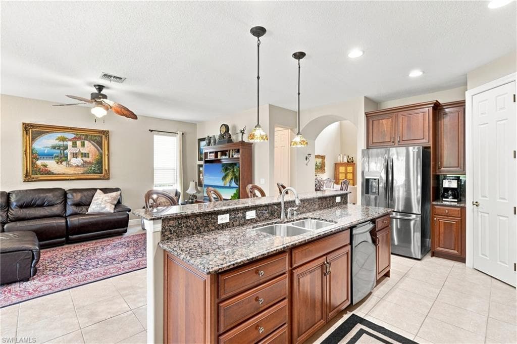 Kitchen island with granite countertops, dual basin stainless steel sink, and pendant lighting