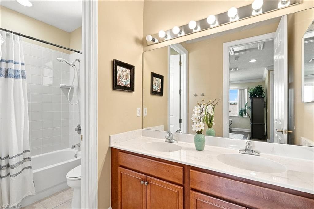 Bathroom featuring a double vanity with wood-finish cabinetry, a large mirror, and a tub with an integrated shower