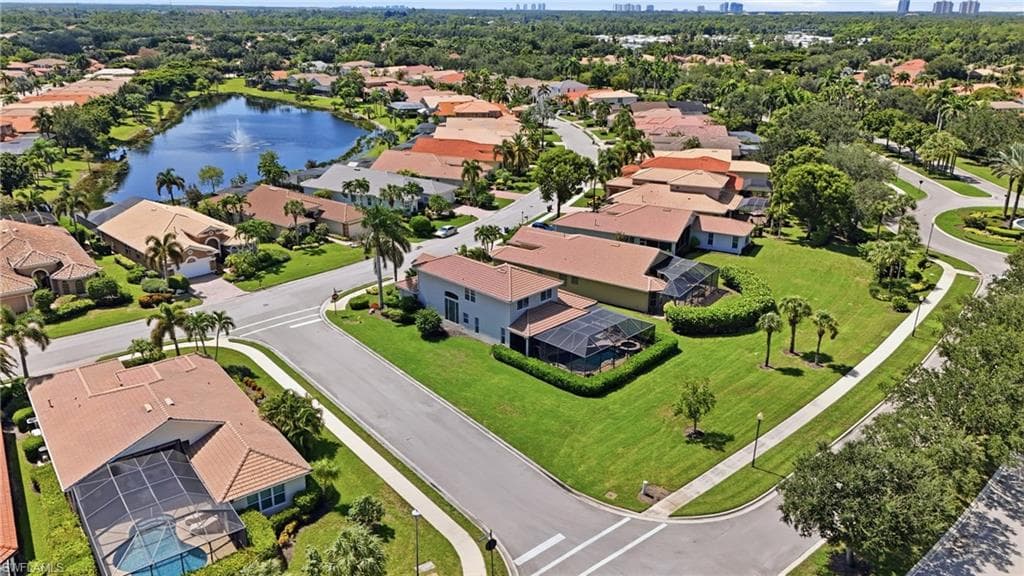 Lush green landscaping and mature trees complement the neighborhood's architecture, featuring terracotta-tiled roofs and screened pools
