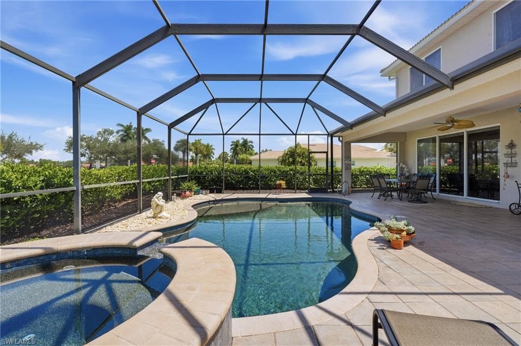 Screened enclosure featuring a freeform pool, integrated spa, and expansive paver patio