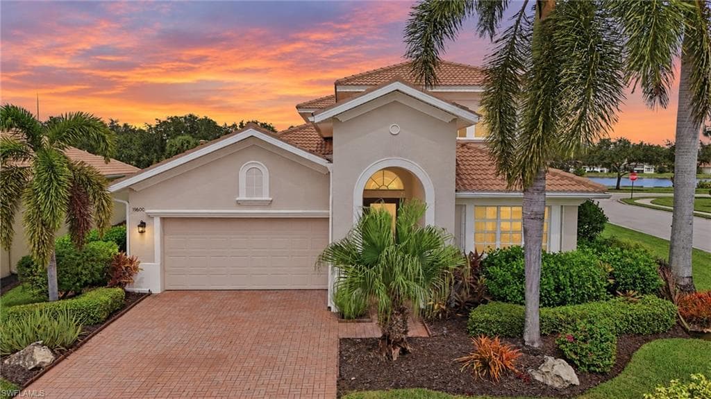 Stucco exterior with a tile roof, arched entryway, and an attached garage