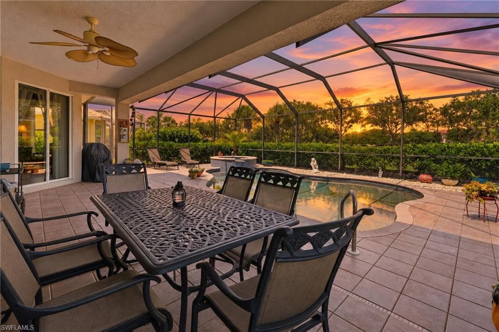 Screened lanai featuring a ceiling fan, a freeform pool, a built-in spa, and a tiled patio
