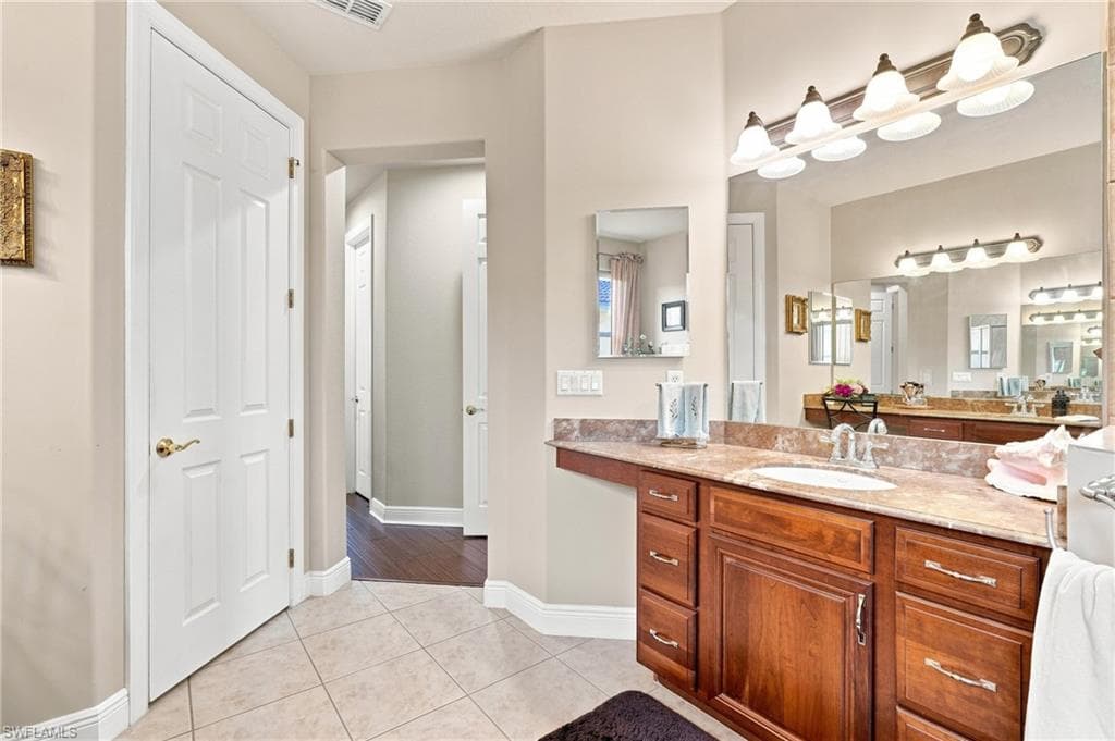 Bathroom vanity with a mounted sink, expansive countertop, and built-in wood cabinetry
