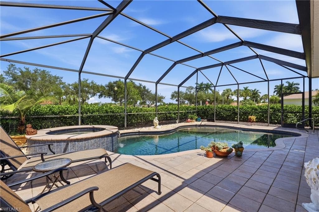 Screened outdoor living area featuring a swimming pool, integrated spa, and paver decking