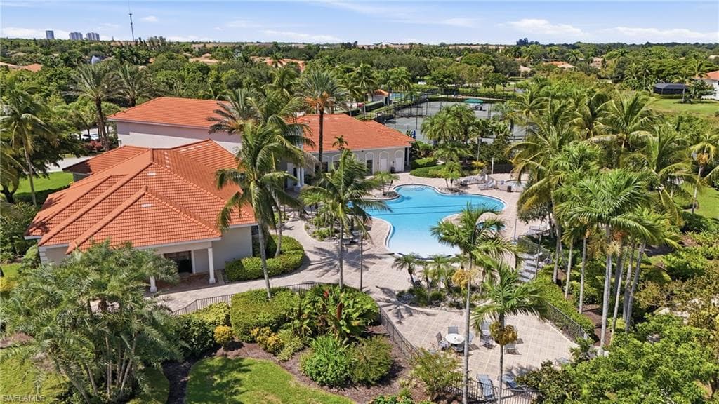 Expansive outdoor amenities featuring a freeform swimming pool, multiple tennis courts, and mature tropical landscaping