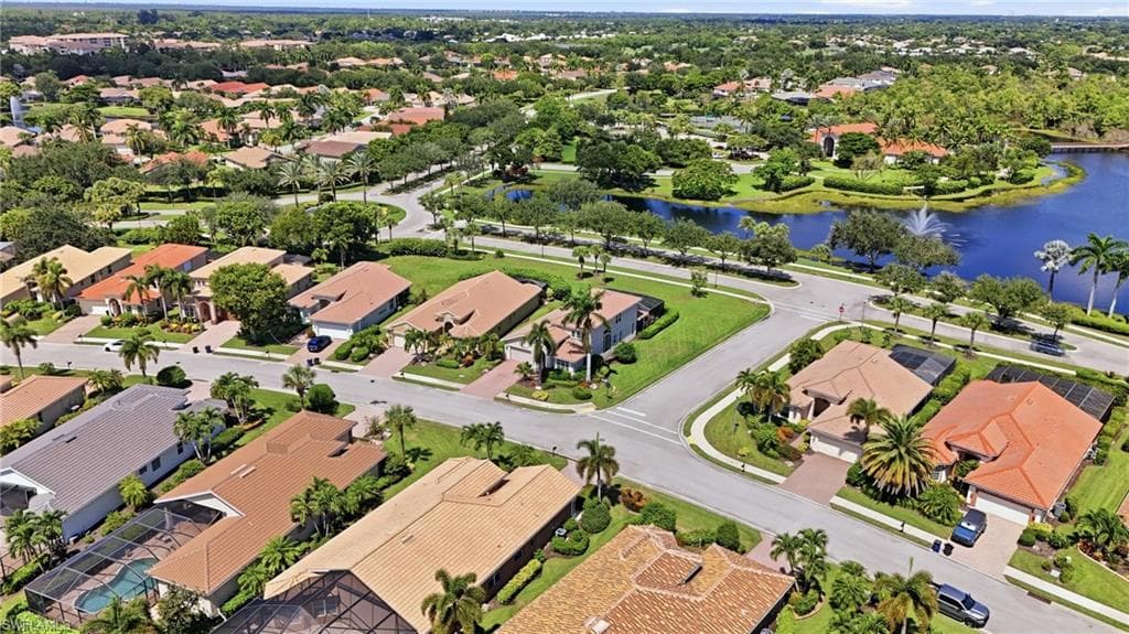 Lush green landscaping with mature trees, a tranquil water feature, and paved roadways