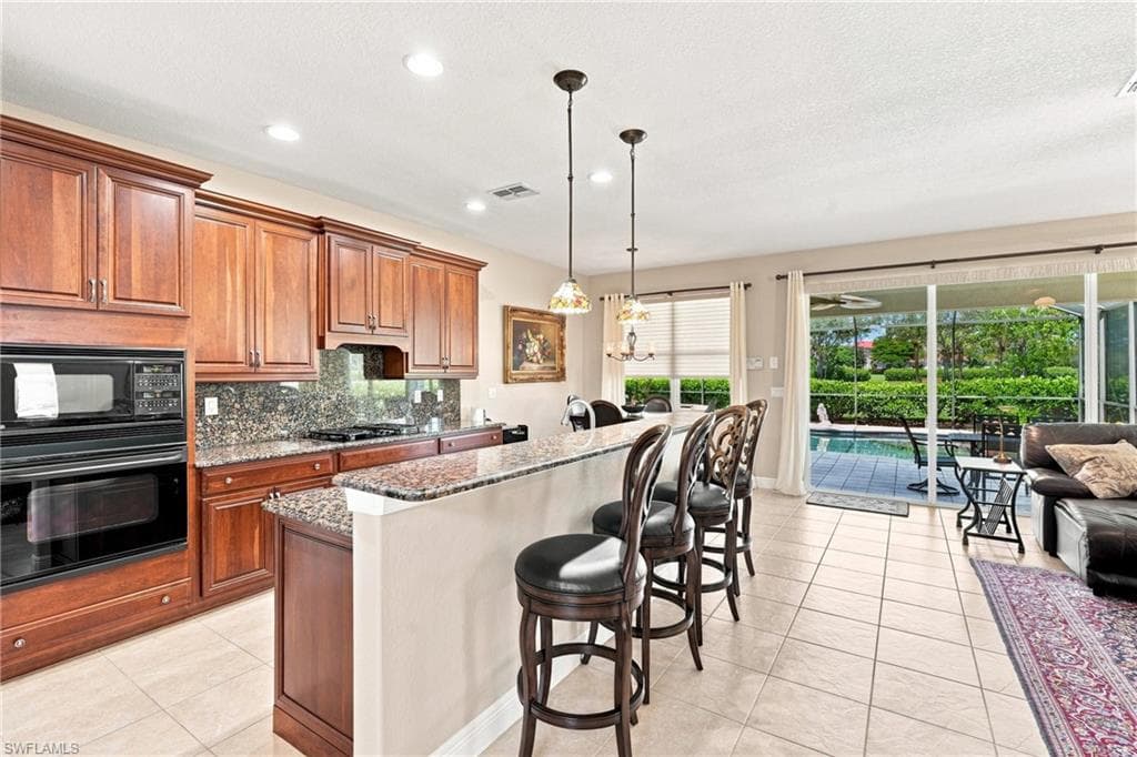 Kitchen featuring wood cabinetry, built-in wall oven and microwave, granite countertops, and tile flooring