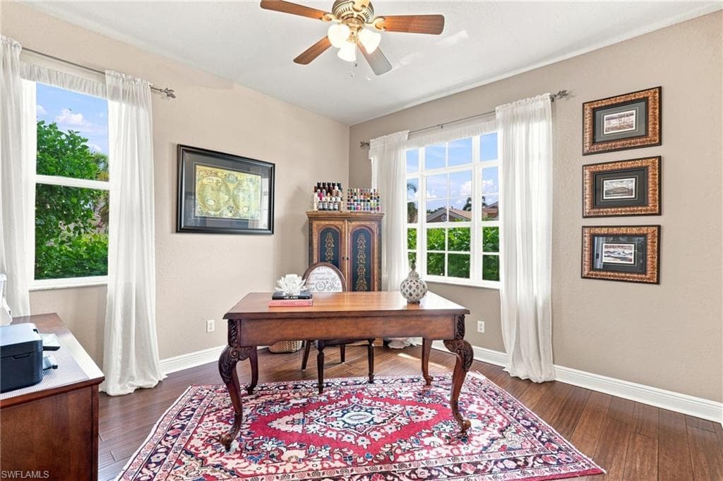 Hardwood flooring, painted walls, ceiling fan, and large windows