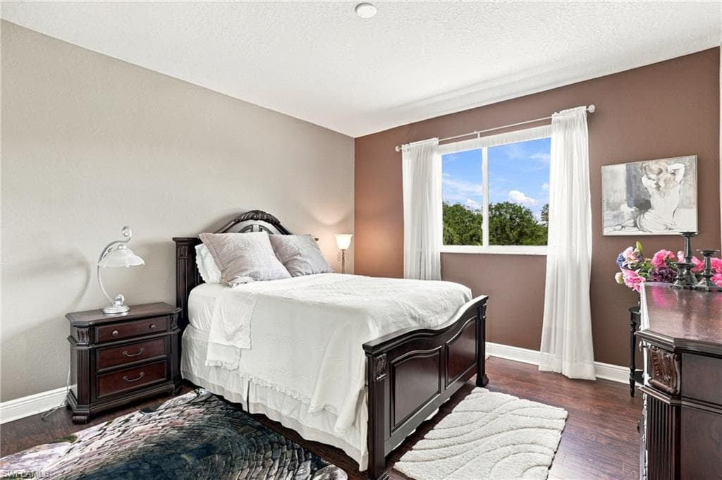 Wood-finish flooring, white trim, and a window with white drapes