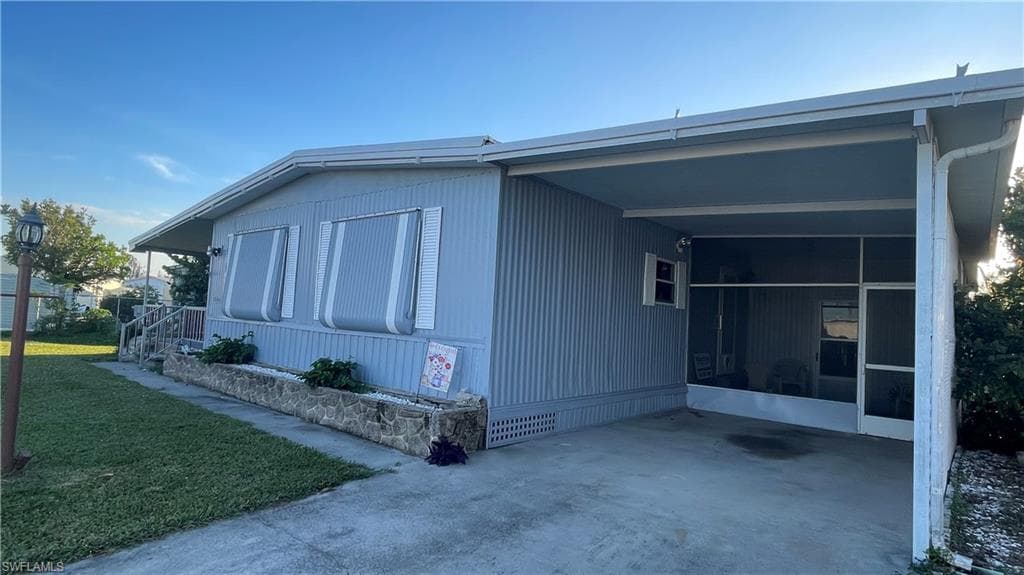 View of side of home with a carport and a lawn