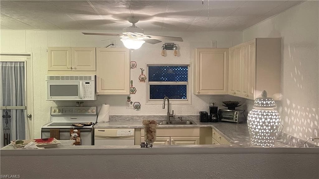 Kitchen with sink, ceiling fan, and white appliances