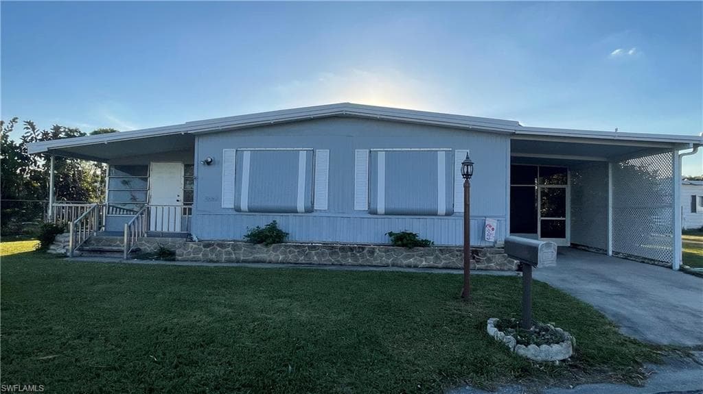 Manufactured / mobile home featuring a front lawn and a carport