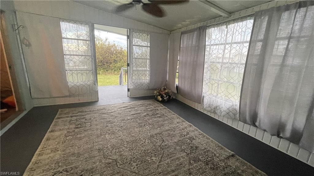 Unfurnished sunroom featuring ceiling fan