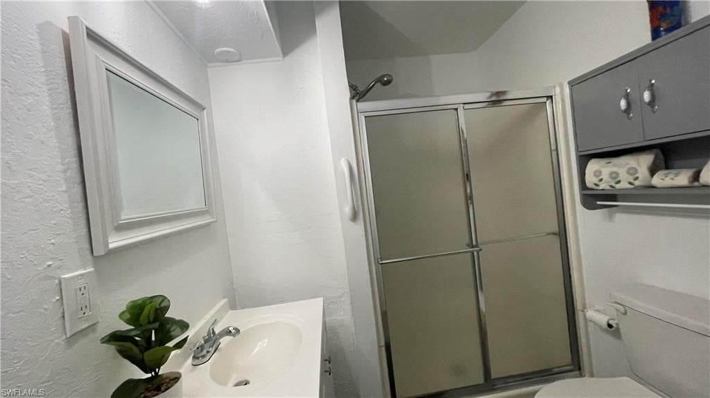 Bathroom with toilet, walk in shower, and vanity