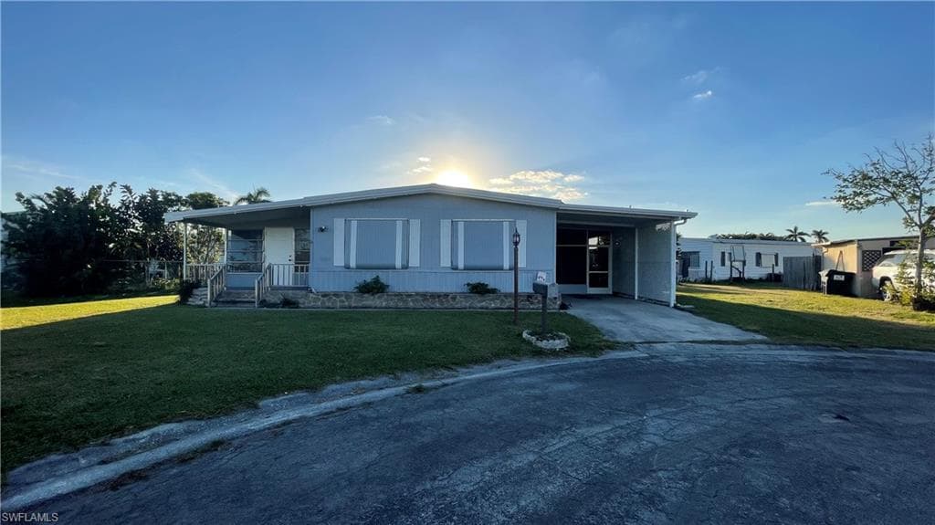 View of front of property featuring a front lawn and a carport