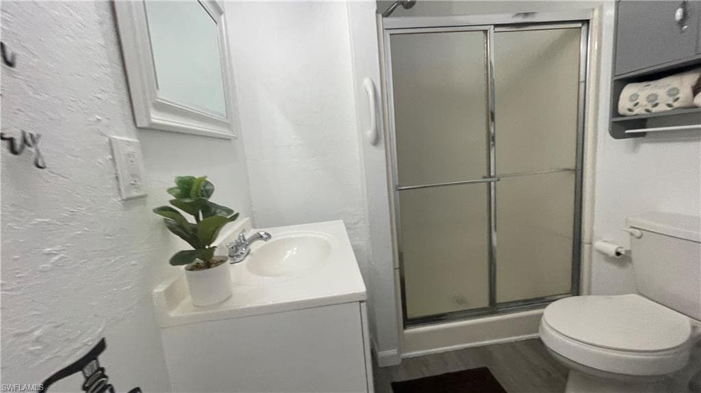 Bathroom featuring vanity, vinyl flooring, walk in shower, and toilet