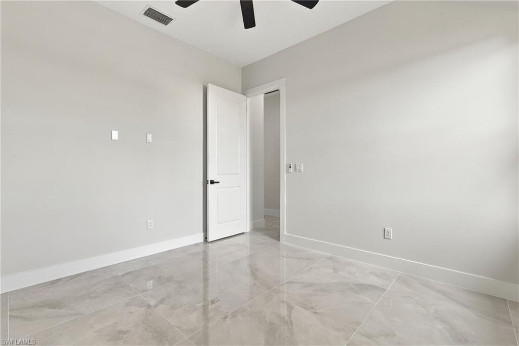 Spacious room with large format tile flooring, a two-panel interior door, and a ceiling fan