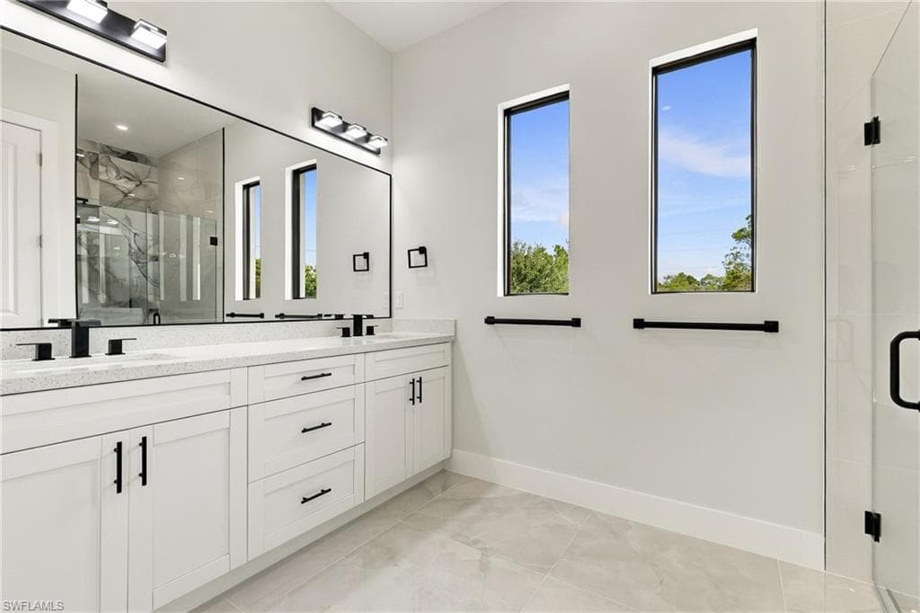 Dual vanity with white cabinetry, matte black hardware, and an expansive mirror