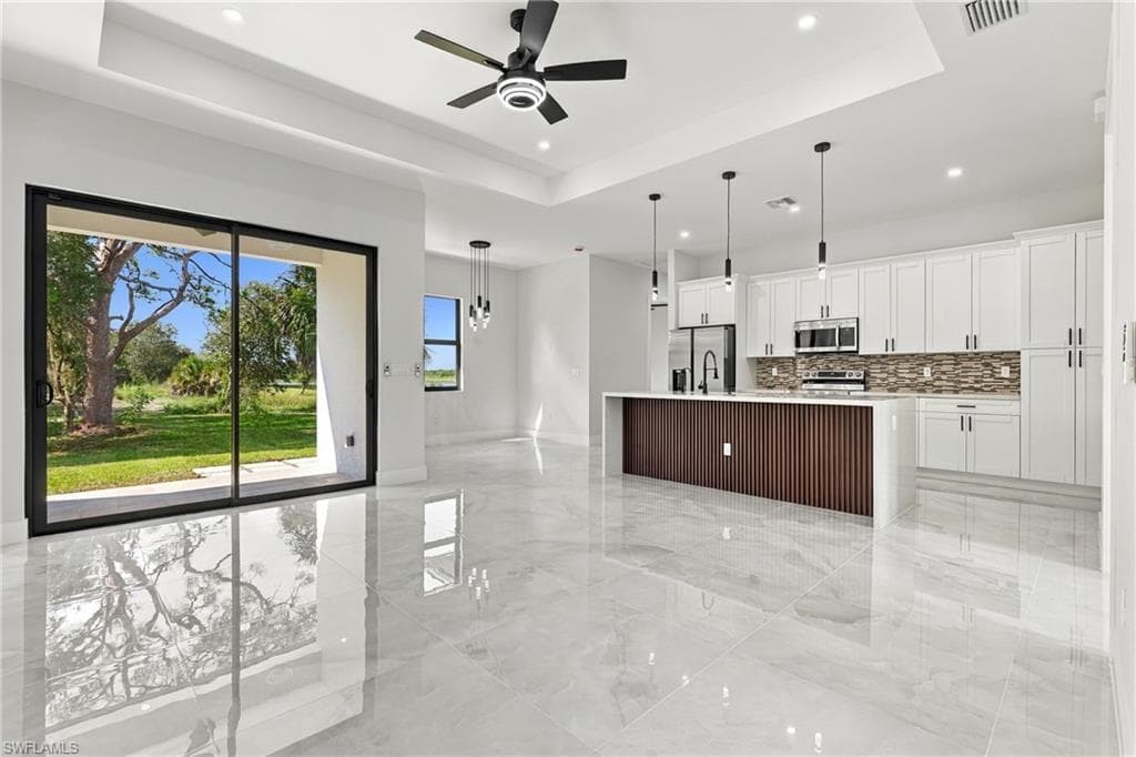 Spacious open-concept living area featuring large format tile flooring and tray ceiling