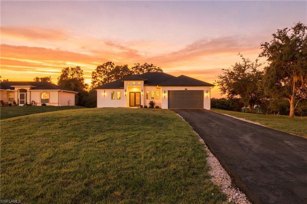 Contemporary architecture with a striking facade, an attached two-car garage, and a paved driveway bordered by decorative stone